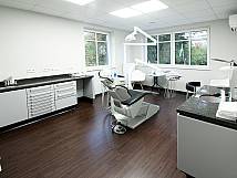 Ansicht eines schwarz-weiß gehaltenen Behandlungszimmers mit braunem Boden