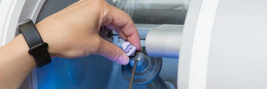 Person präpariert Zahnimplantat in einem CEREC-Gerät