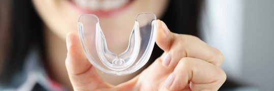 Frau präsentiert stolz eine Zahnschiene